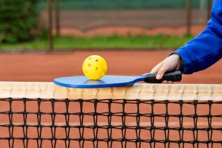 Accessoires de pickleball : balles, filet portable, grip et sac de transport sur un terrain