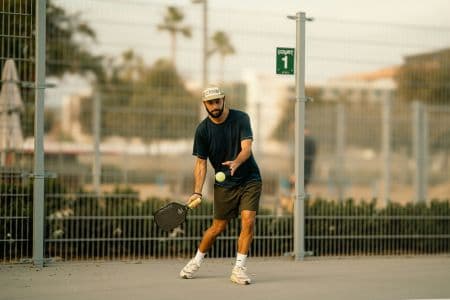 Joueur de pickleball en position de service, raquette sous la taille et geste ascendant
